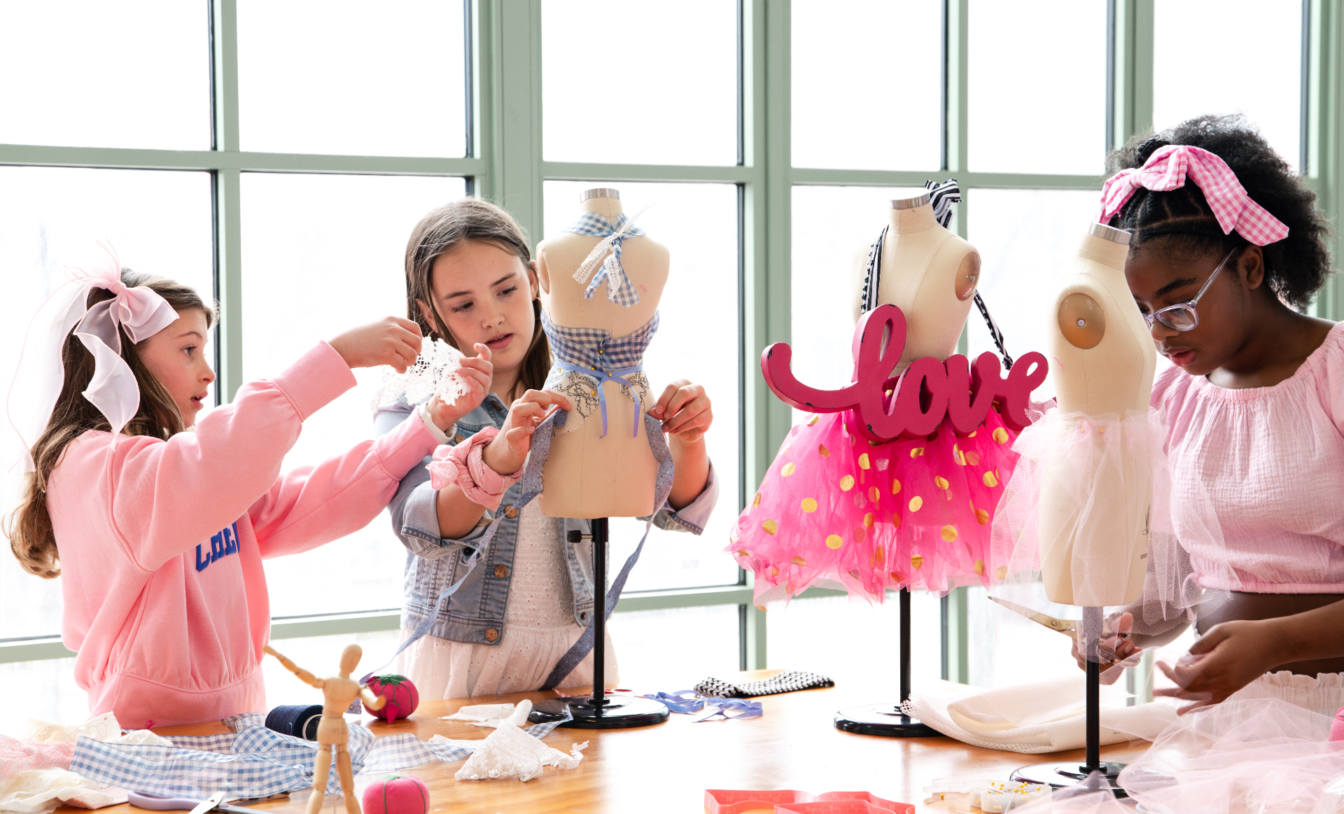 Future Fashion Stars™ students collaborating around dress forms in a bright studio classroom